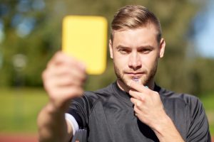 Referee on football field showing yellow card