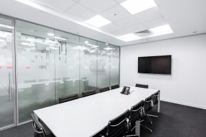 Offices conference room with white desk and monitor on the wall