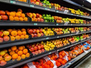 A shelf full of fruit and vegetables in a supermarket