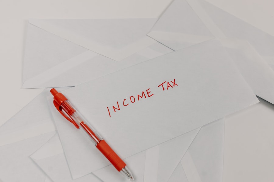 Red pen next to a white envelope with the words "Income Tax"